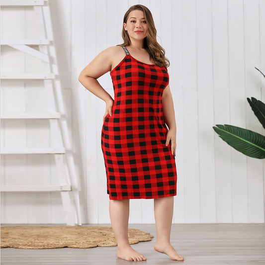 Woman wearing a red and black checkered dress standing in a room with white walls and a wooden floor.