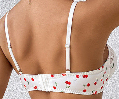 Person wearing a white bikini top with red patterns and blue jeans against a white background