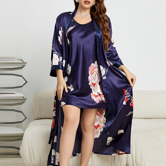 Woman wearing a navy floral satin robe over a matching nightgown in a minimalistic room.