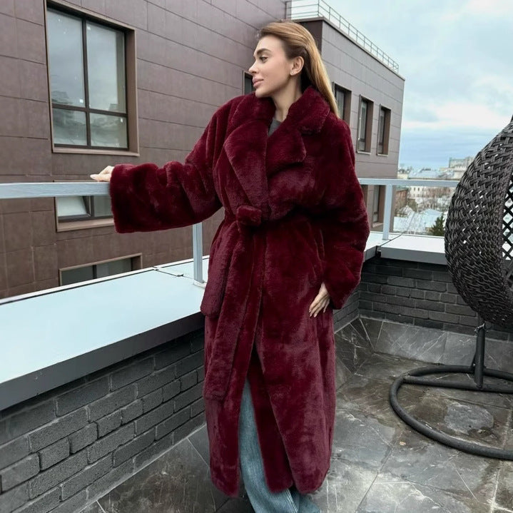 Woman in a burgundy coat standing on a rooftop with a cityscape background